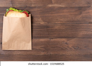 delicious panini in paper bag on wooden background. concept of eco packages of recyclables. still life