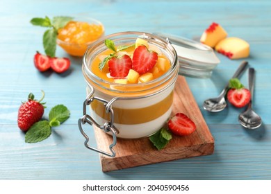 Delicious Panna Cotta With Mango Coulis And Fresh Fruit Pieces On Light Blue Wooden Table