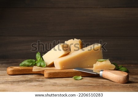 Delicious parmesan cheese with basil and knife on wooden table