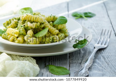 delicious pasta dish with creamy spinach sauce decorated with spinach leaves on grey wooden background