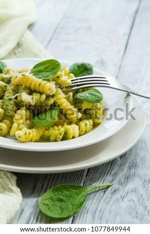 delicious pasta dish with creamy spinach sauce decorated with spinach leaves on grey wooden background