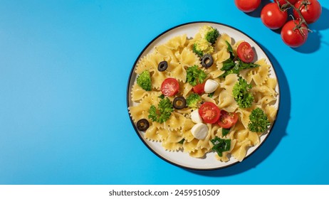 Delicious pasta salad with farfalle, cherry tomatoes, olives, mozzarella, broccoli, and parsley on a blue background. - Powered by Shutterstock