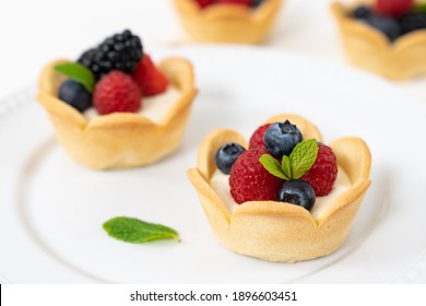 Delicious pastry mini fruit cream cheese pies or tart cakes with fresh raspberry, blueberry and blackberry - Powered by Shutterstock