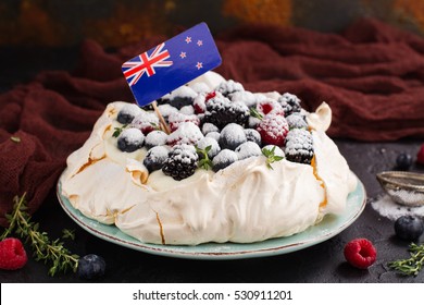Delicious Pavlova cake with cream, berries thyme and New Zealand flag over dark background. Space for text. Selective focus