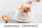 Delicious Pavlova cake with fresh blueberry, figs, peach and mascarpone on white background. Close up. Confectionery, recipe, menu. Yummy meringue summer dessert