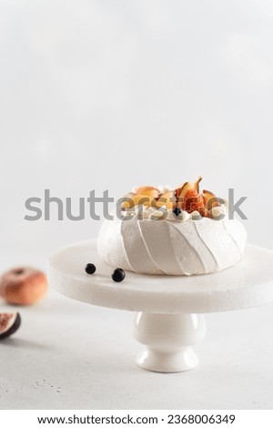 Delicious Pavlova cake with fresh blueberry, figs, peach and mascarpone on white background. Vertical, copy space. Confectionery, recipe, menu. Yummy meringue summer dessert with berries