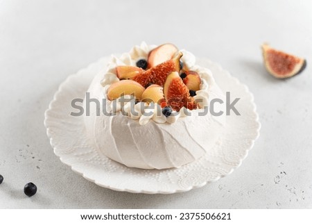 Delicious Pavlova cake with fresh blueberry, figs, peach and mascarpone on white background. Close up. Confectionery, recipe, menu. Yummy meringue summer dessert with berries