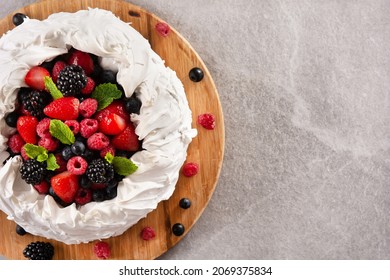 Delicious Pavlova cake with meringue topped and fresh berries on gray stone. Copy space