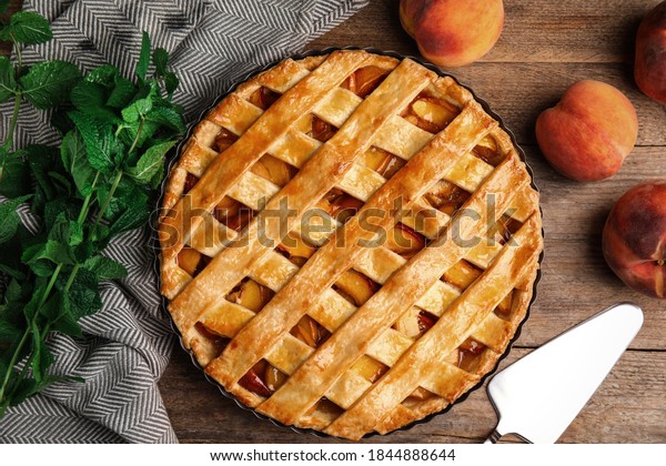 Delicious peach pie and fresh fruits on wooden table,\
flat lay