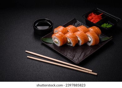 Delicious Philadelphia sushi roll with salmon, shrimp, cucumber and cream cheese on a dark concrete background - Powered by Shutterstock