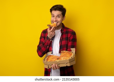 Delicious Pizza. Excited Young Man Enjoying Eating Tasty Pizza Holding Carton Pizzeria Box Standing Posing Over Yellow Orange Studio Background. Cheat Meal, Nutrition And Fast Food Overeating
