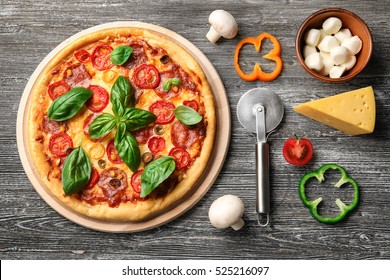Delicious pizza with ingredients and spices on table