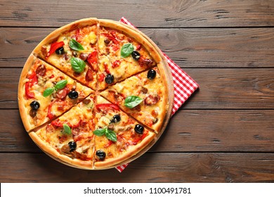 Delicious pizza with olives and sausages on wooden table, top view