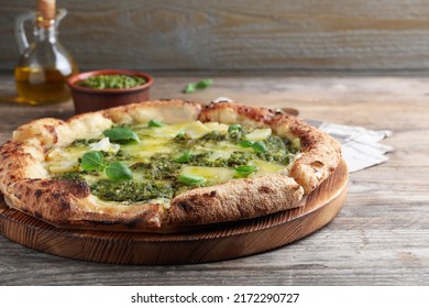 Delicious pizza with pesto, cheese and basil on wooden table
