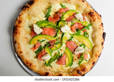 Delicious pizza with salmon, cheese, avocado and fresh arugula. Over white background. Fast food, junk food concept. Italian pizza recipe. - Powered by Shutterstock