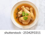 A delicious plate of cooked chicken drumsticks served in a savory broth with fresh herbs, perfect for a comforting meal.