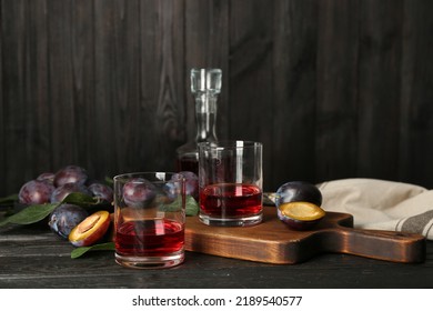 Delicious Plum Liquor And Ripe Fruits On Black Wooden Table. Homemade Strong Alcoholic Beverage