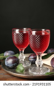 Delicious Plum Liquor And Ripe Fruits On Wooden Table Against Black Background. Homemade Strong Alcoholic Beverage