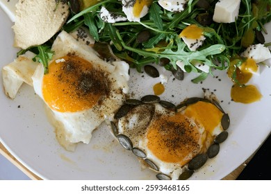 Deliciosos huevos pochados servidos artísticamente junto con una ensalada de rúcula fresca y vibrante cubierta con crujientes semillas de calabaza