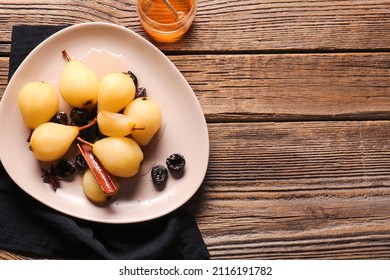 Delicious poached pears with prunes, anise, cinnamon in dish on wooden background