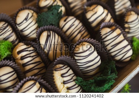 Delicious profiteroles with chocolate glaze on wooden tray
