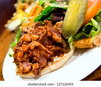 Delicious pub style pulled pork sandwich with pickle and salad on the side