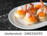 Delicious puff pastry with shrimps, cream cheese and red caviar on dark table, closeup