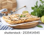 Delicious puff pastry tart with pears, almond, mint and blue cheese on white table, closeup