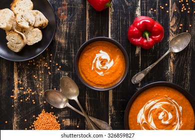 Delicious Pumpkin Soup With Heavy Cream On Dark Rustic Wooden Table With Red Bell Pepper, Bread Toasts, Lentil. Top View