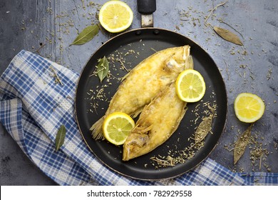 Delicious Ready Sole Fish On Black Pan And Decorated With Lemon And Herbs