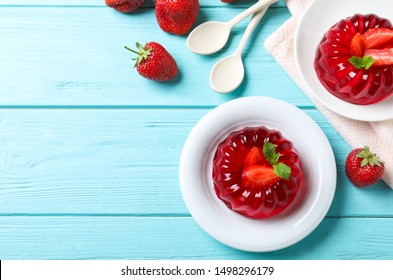 Delicious red jelly with strawberries and mint on light blue wooden table, flat lay. Space for text