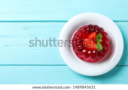 Delicious red jelly with strawberry and mint on light blue wooden table, top view. Space for text