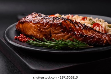 Delicious red salmon fish grilled with sauce and sesame seeds with rice, vegetables, spices and herbs on a dark concrete background - Powered by Shutterstock