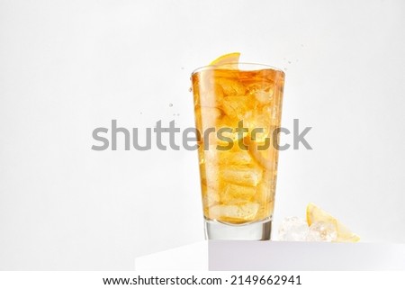 Delicious refreshing summer iced tea in a glass with drops. Sunshine. Copy space. Ice tea, cold lemonade with lemon