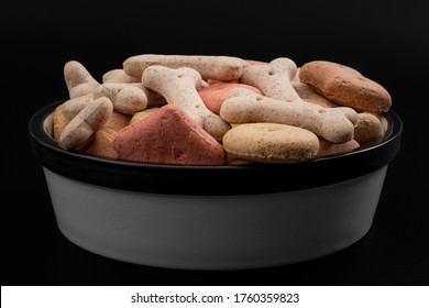 Delicious Reward Treat, Dry Food And Pet Nutrition Concept With Low Angle Picture Of Bowl Full Of Many Dog Treats Isolated On Black Background With Clipping Path Cutout