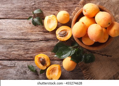 Delicious ripe apricots in a wooden bowl on the table close-up. Horizontal view from above