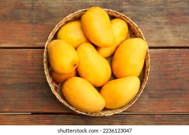 Delicious ripe juicy mangos on wooden table, top view
