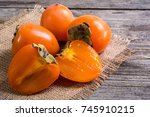 Delicious ripe persimmon fruit on wooden background