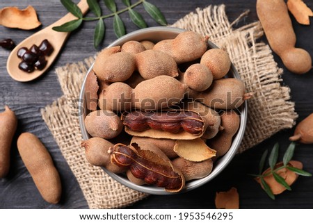 Delicious ripe tamarinds on black wooden table, flat lay