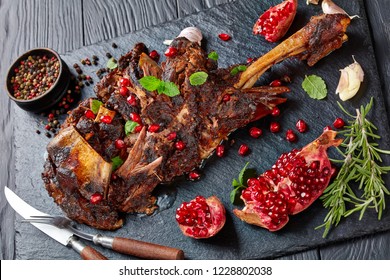 Delicious Roast Shoulder Of Lamb With Pomegranate Seeds, Mint Leaves, Spices And Rosemary On A Black Slate Plate On A Wooden Table,view From Above, Close-up