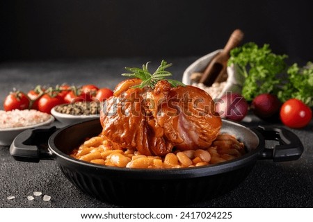 Delicious Roasted Smoked pork knuckle with beans stew, vegetables, herbs and spices on dark background. Romanian Traditional Food.