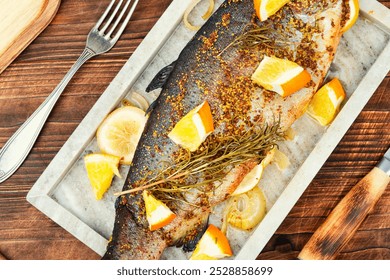 Delicious roasted trout seasoned with spices and orange on a stone serving board on wooden background. Close up. - Powered by Shutterstock