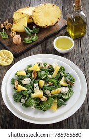 Delicious Salad Of  Baby Spinach Leaves, Pineapple Slices, Blue Cheese And Walnuts With Ingredients On Cutting Board And Olive Oil, Lemon Dressing At Background, Vertical View From Above