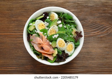 Delicious salad with boiled eggs, salmon and cheese in bowl on wooden table, top view - Shutterstock ID 2205485179