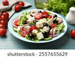 Delicious salad with feta cheese served on blue wooden table, closeup