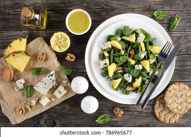 Delicious Salad Of Spinach Leaves, Pineapple Slices, Blue Cheese And Walnuts With Ingredients On Paper, Bottle With Olive Oil, Lemon Dressing At Background, Close-up