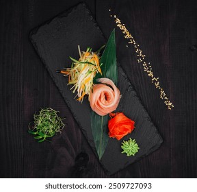 Delicious salmon sashimi served on a black slate plate, garnished with ginger, wasabi and sesame seeds - Powered by Shutterstock