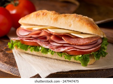 A Delicious Sandwich With Cold Cuts, Lettuce, Tomato, And Cheese On Fresh Ciabatta Bread.