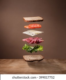 Delicious Sandwich With Floating Ingredients On The Wood Table 