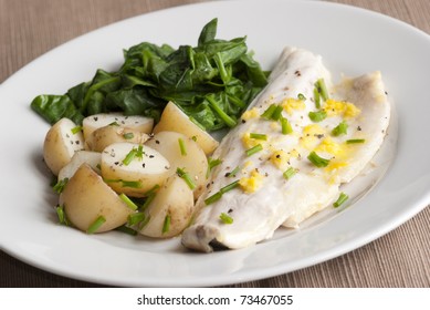 Delicious Seabass With New Potatoes And Spinach On A Plate